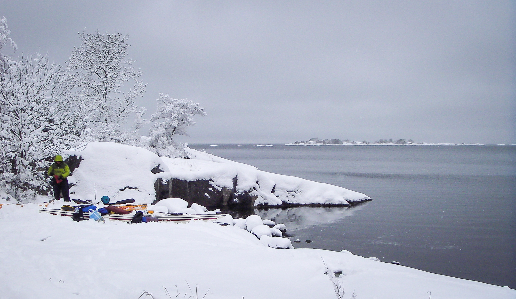 Paddlare packar kajak på översnöade klippor. Norrpada, Stockholms skärgård.