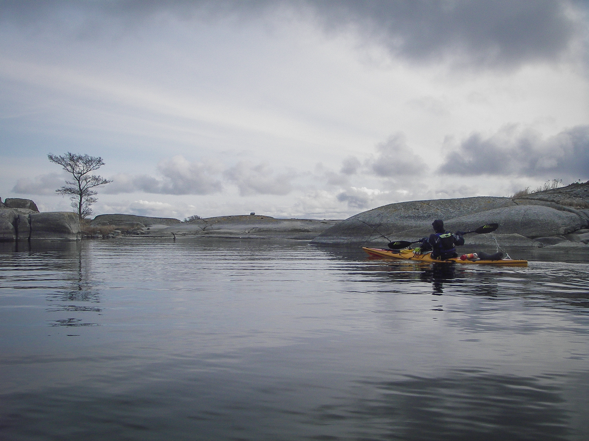 Havskajakpaddlare paddlar i lugnt vatten mellan ytterskären i Stockholms skärgård.