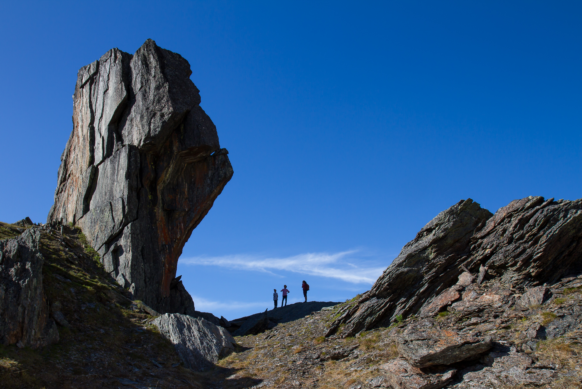 Silhouettes of hikers tells the scale of giant boulder in Kärkevagge.