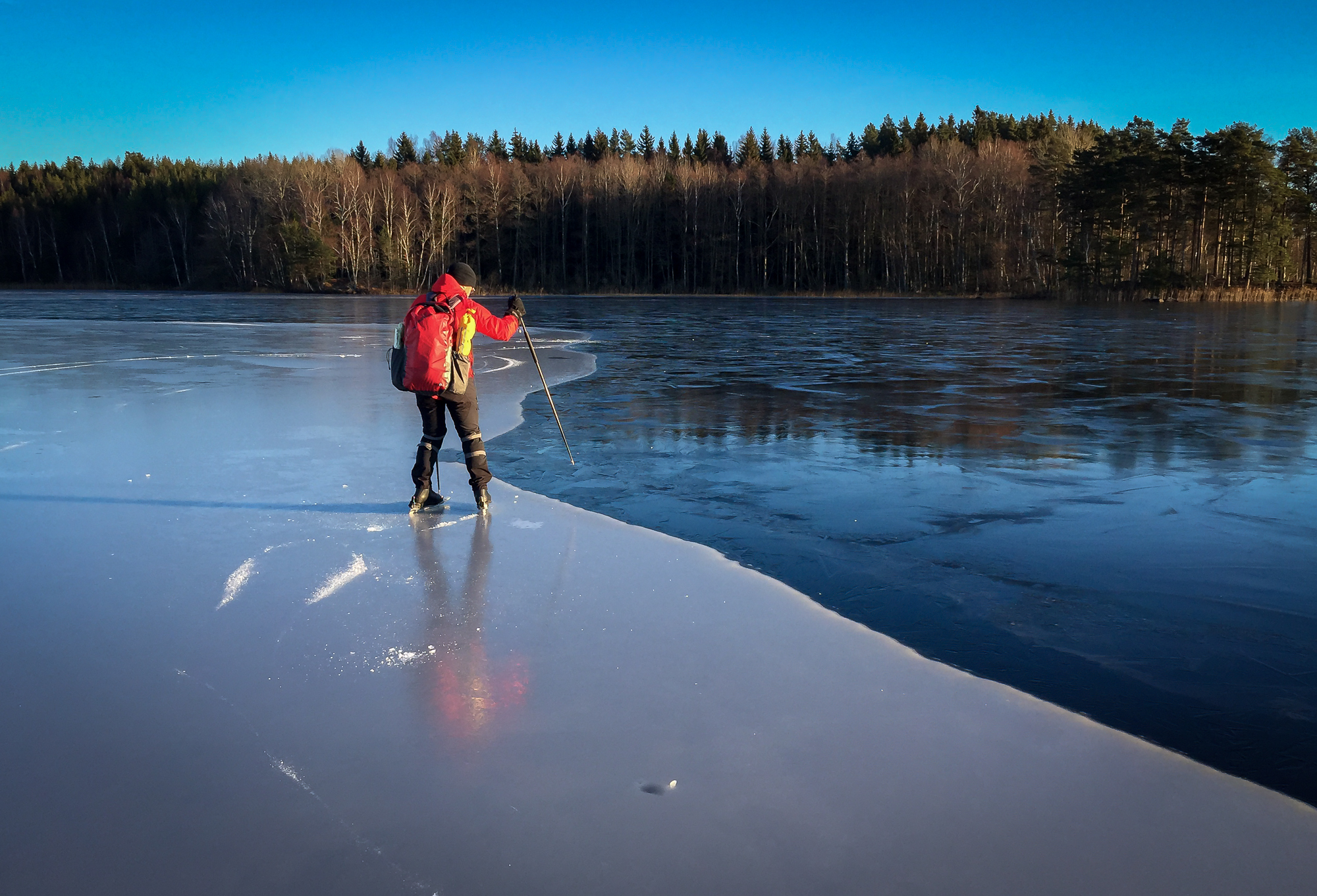 Långfärdsskridskoåkare känner sig fram längs kanten mot tunnare is.