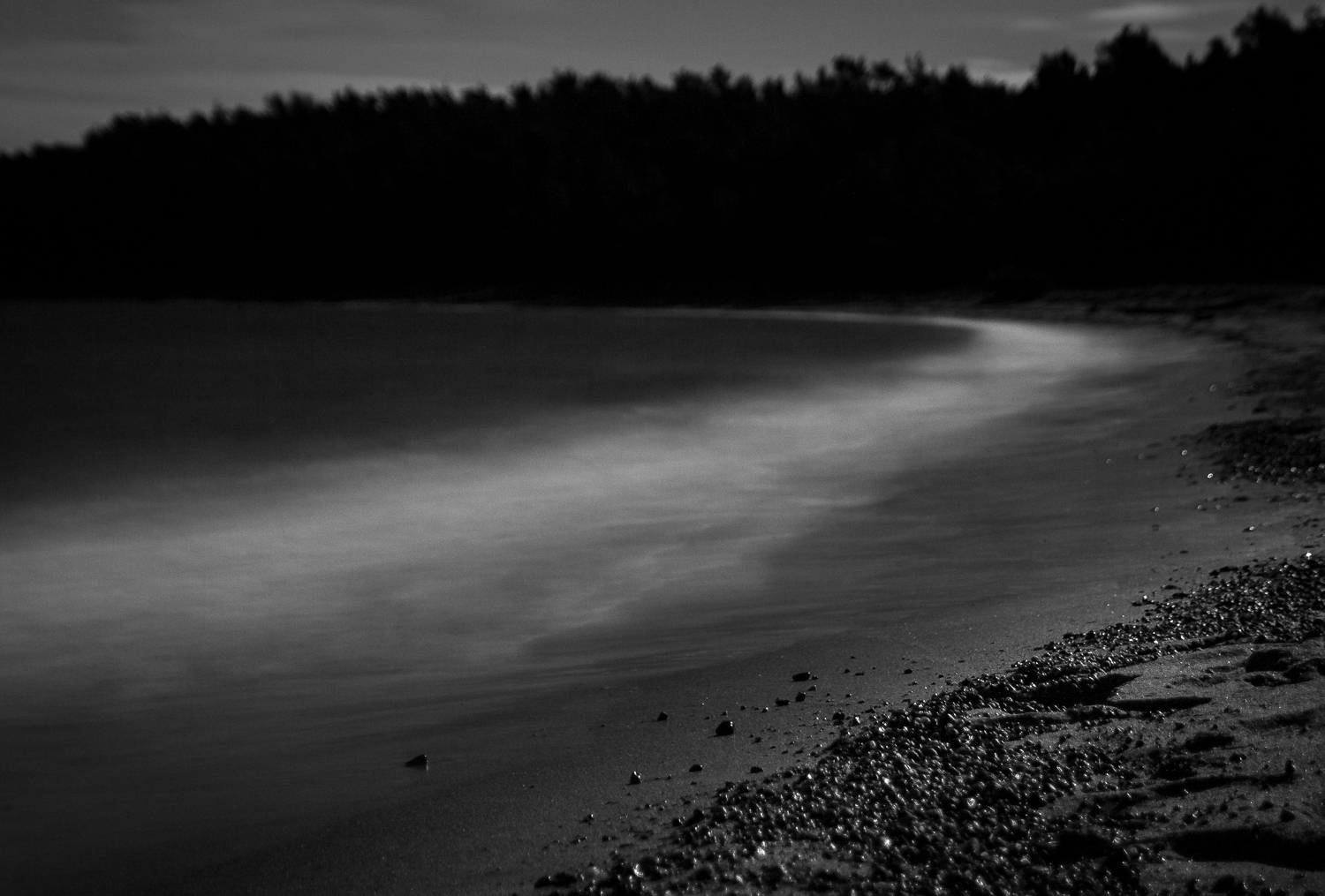Waves hitting a beach in moonlight