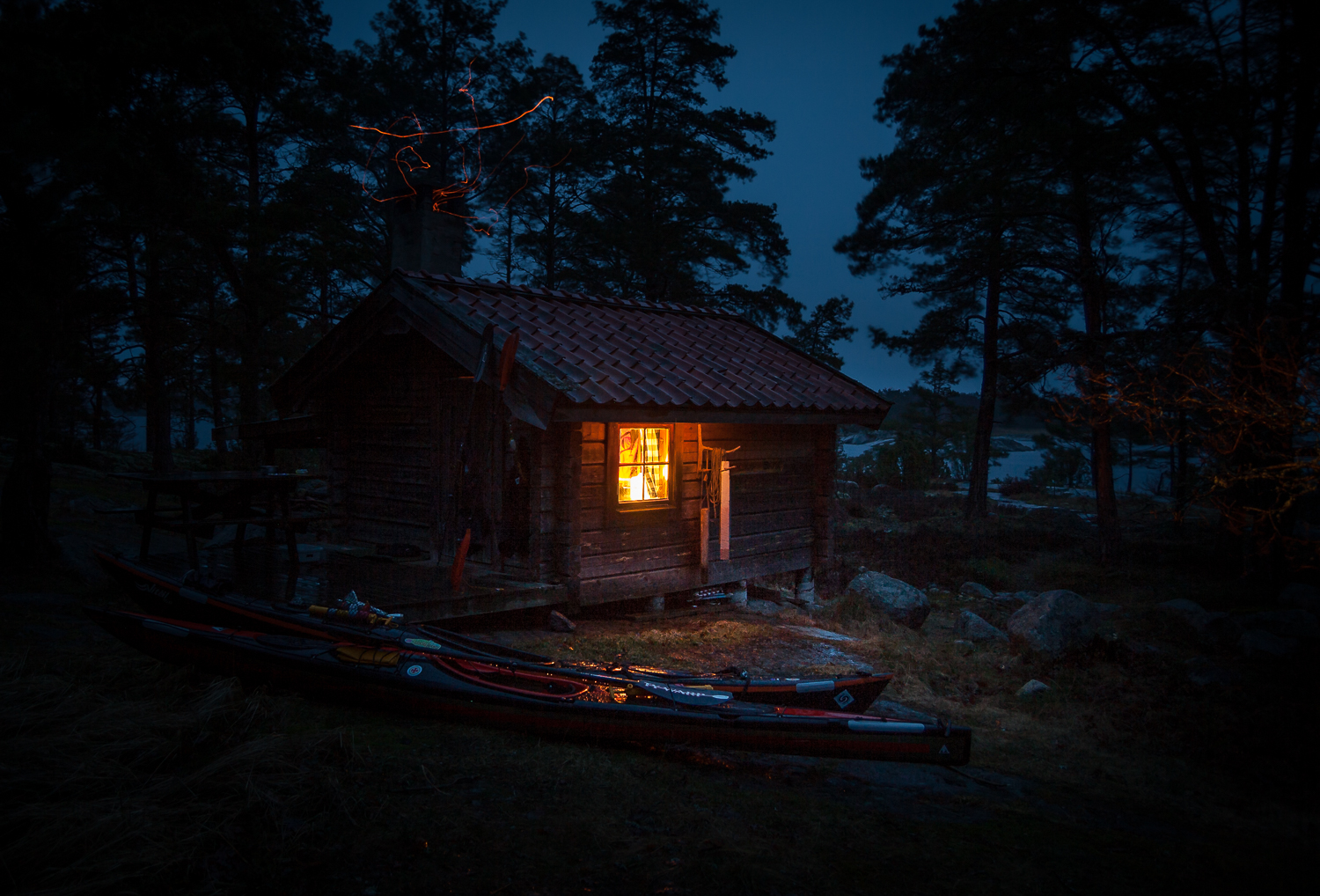 Två kajaker ligger i mörkret utanför en stuga i Stockholms skärgård