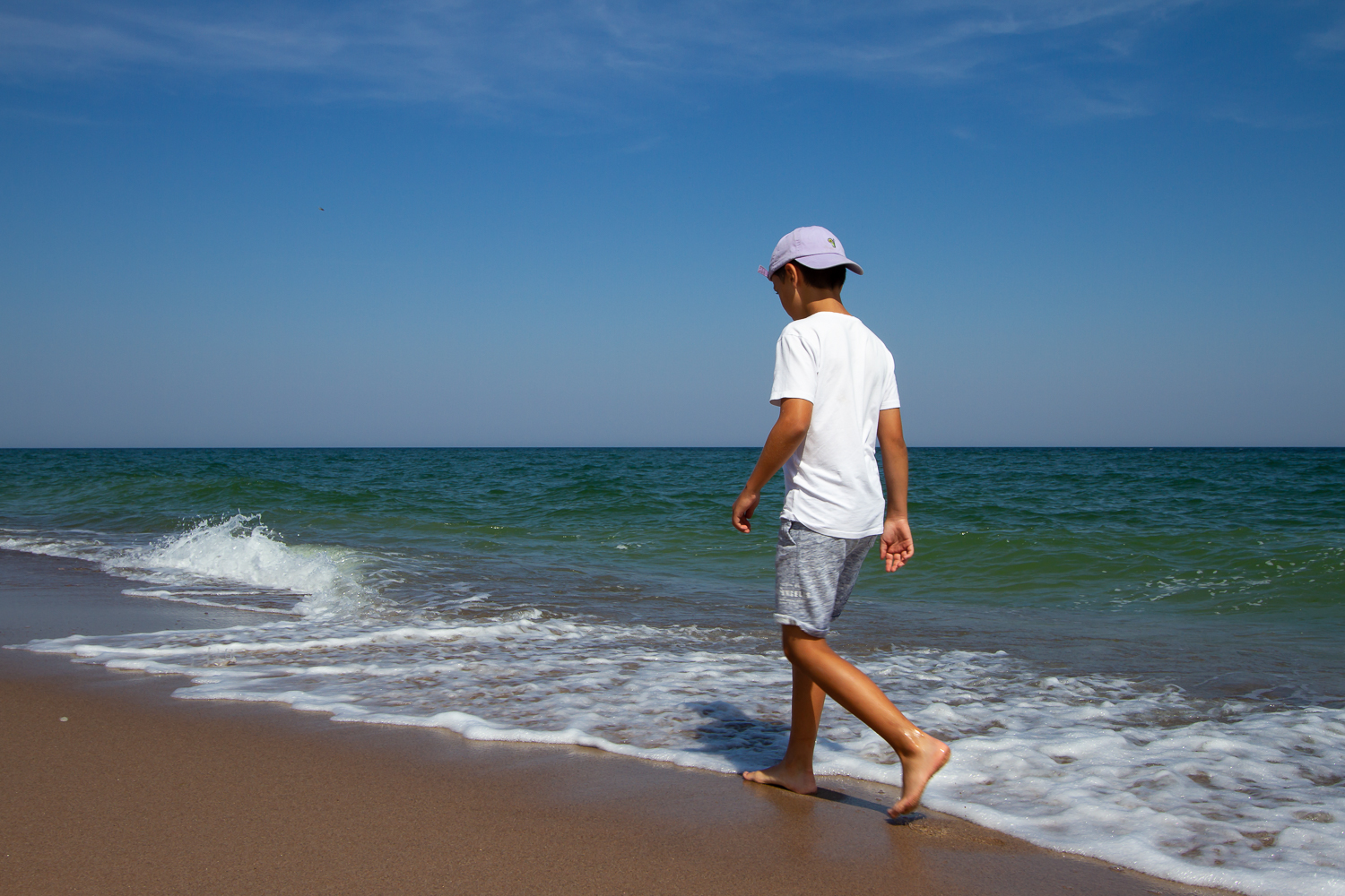 En kille promenerar längs strandkanten på en av Gotska Sandöns underbara stränder