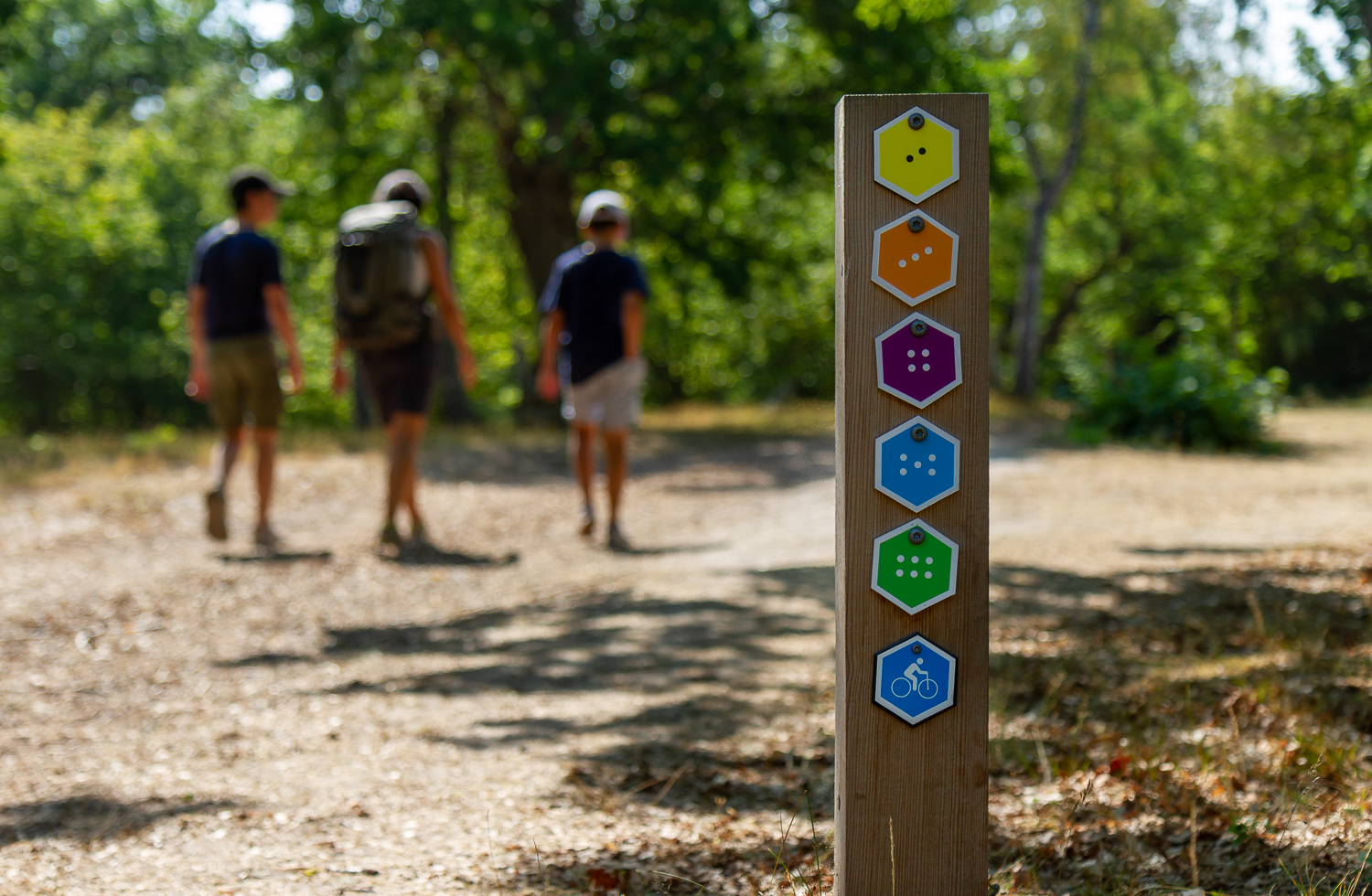 Tre personer vandrar förbi en ledmarkering på Gotska Sandön