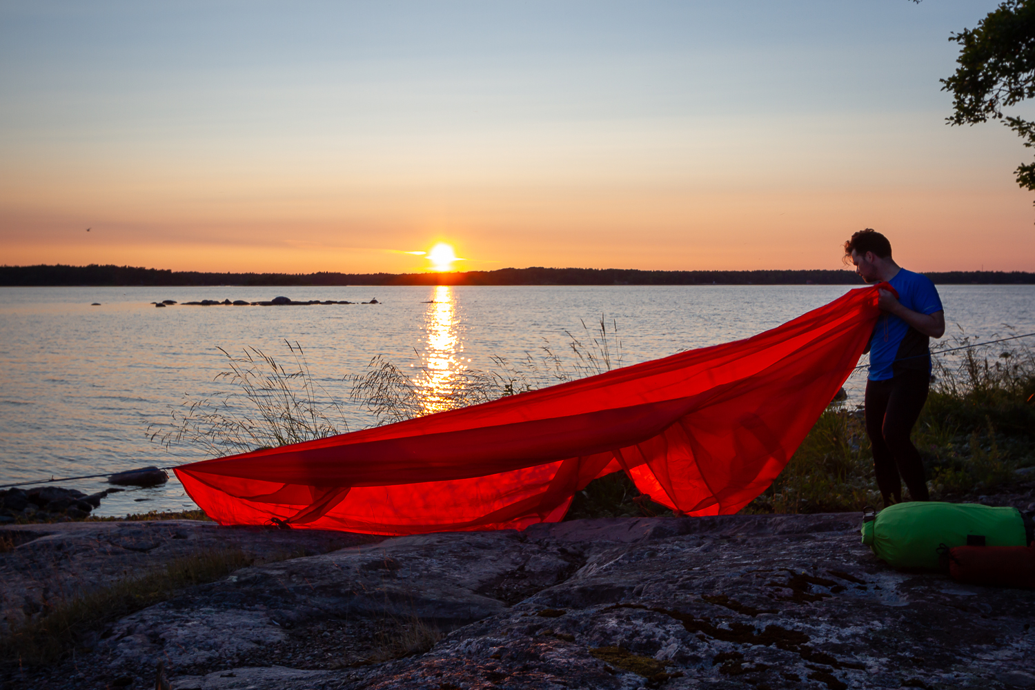 En person förbereder en tarp för sonplats i solnedgången