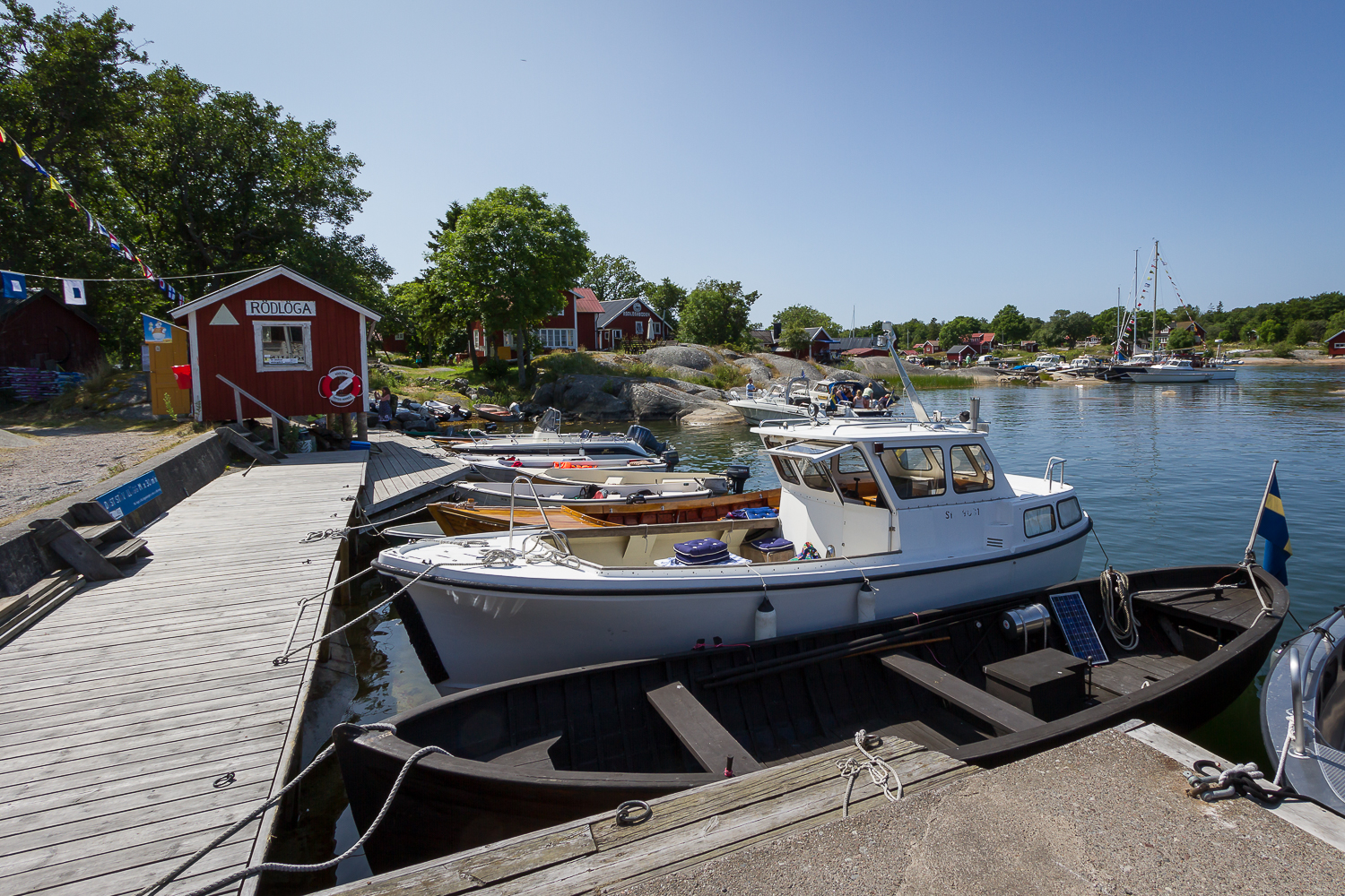 Fritidsbåtar ligger vid gästbryggan i Rödlöga hamn, Stockholms skärgård