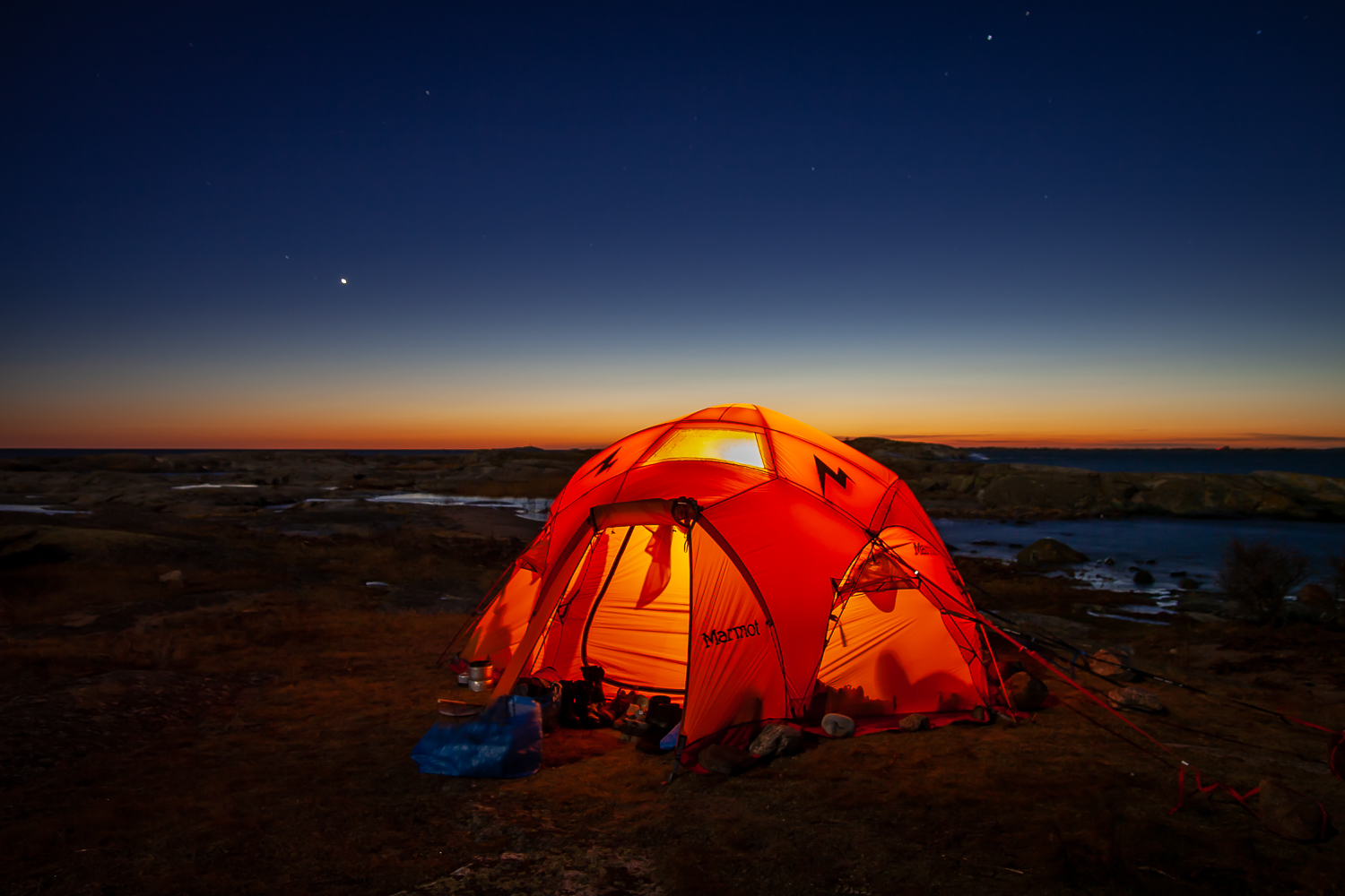 Ett upplyst tält på Tärnskär med det sista färgstarka ljuset vid horisonten i bakgrunden
