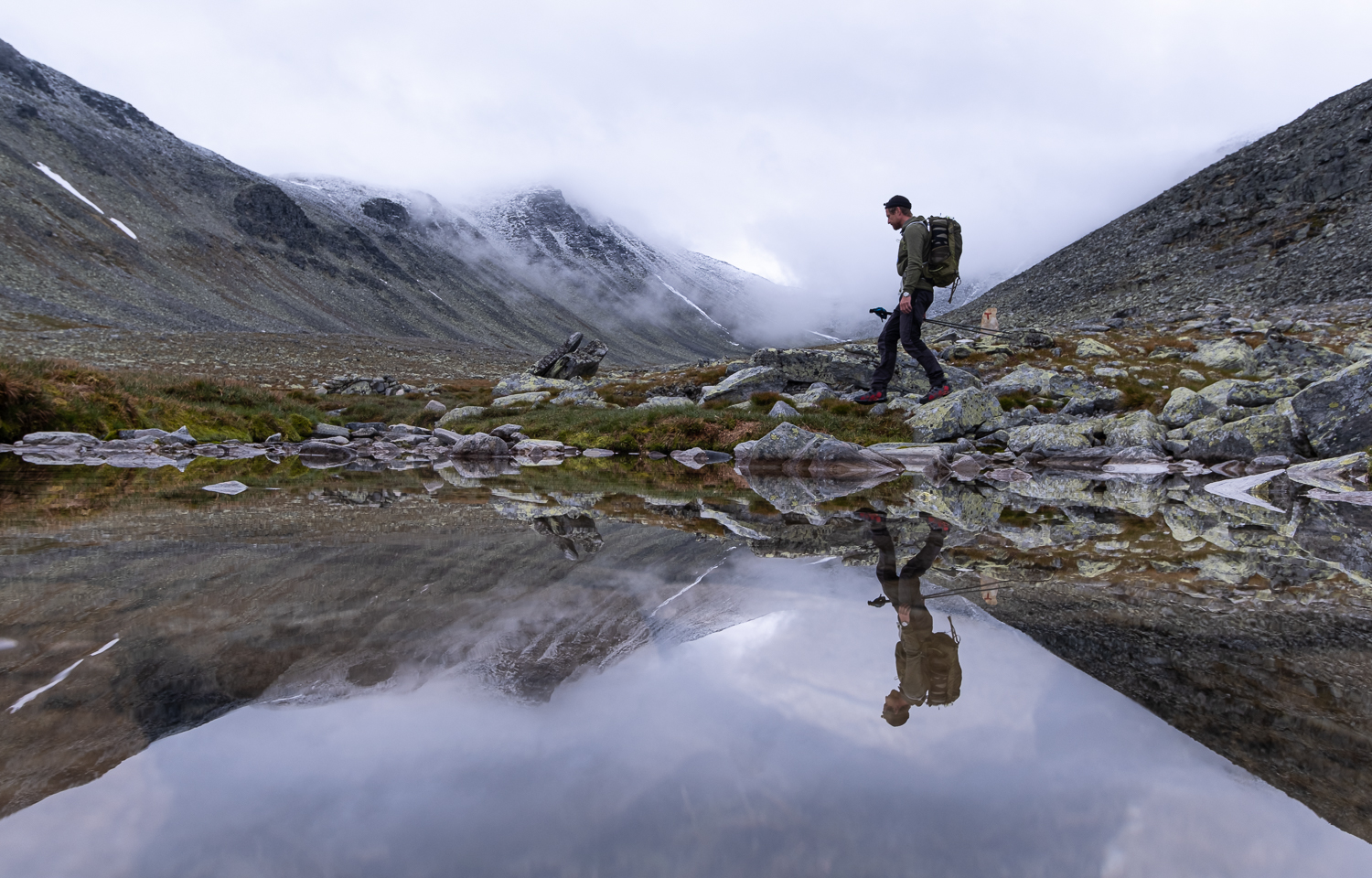 Reflektion i vattnet av en person som vandrar i Rondane nationalpark, Norge