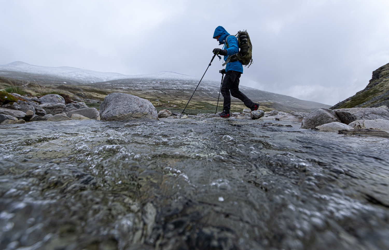 En person vandrar över en bäck i Rondane nationalpark, Norge